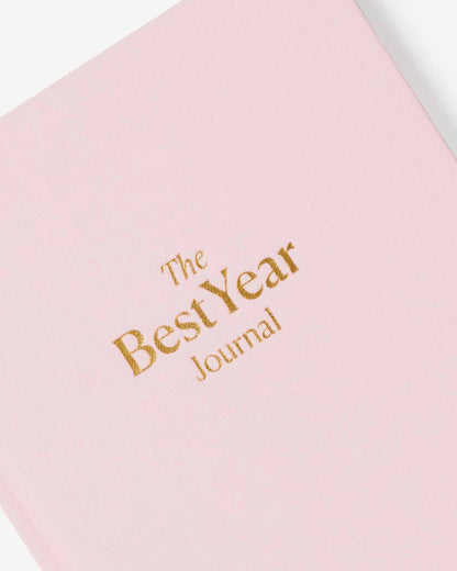 Pink journal with 'The Best Year Journal' text in gold on a white background