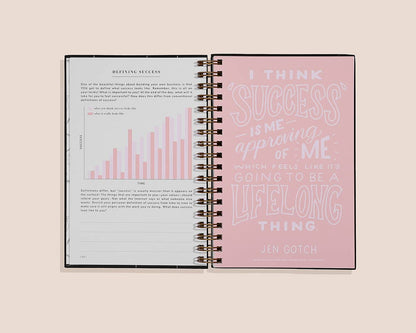 Open spiral-bound notebook with text on a light pink background