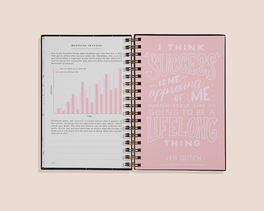 Open spiral-bound notebook with text on a light pink background