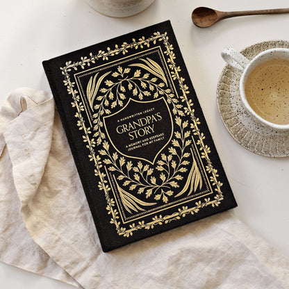 Decorative journal titled 'Grandpa's Story' on a table with a cup of coffee and a spoon.