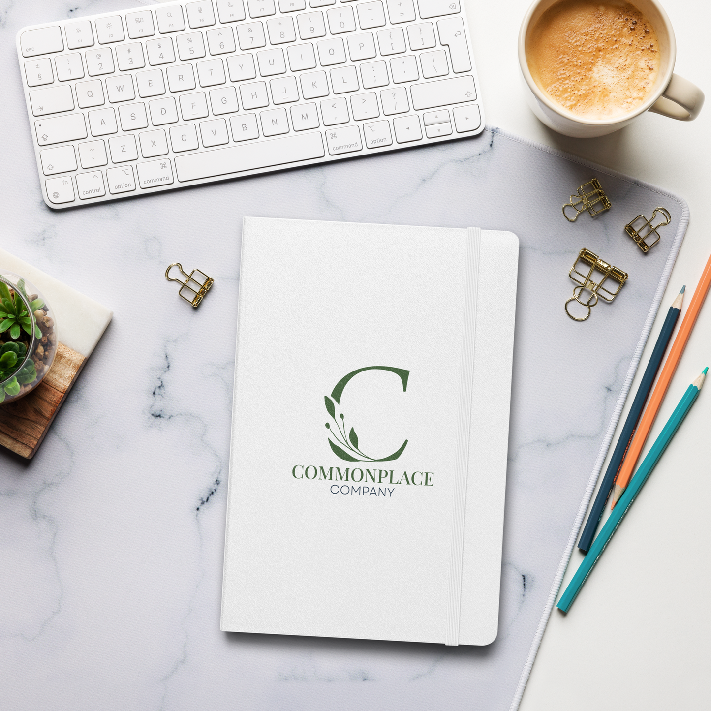 Notebook with 'Commonplace Company' logo on a marble surface with office supplies.