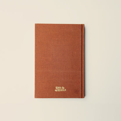 Brown notebook with a logo on a beige background